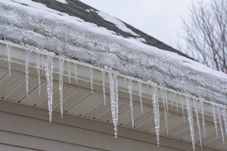 Ice dams and icicles built up along the eave of a roof in winter